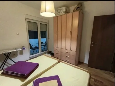 Jednostavna spavaća soba sa dva kreveta, ormarom i izlazom na terasu. - image 6