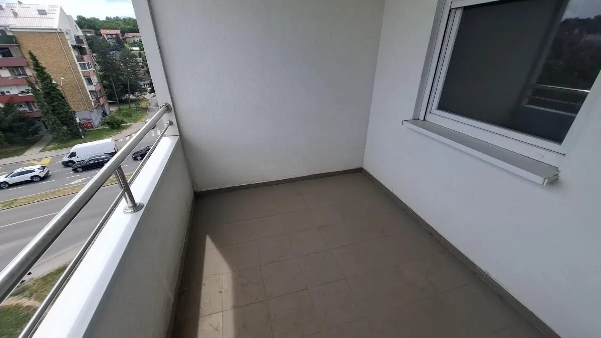 Prazan balkon sa pločicama i pogledom na ulicu.