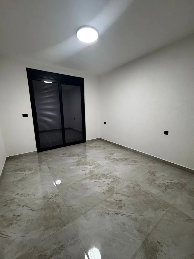 Empty room with ceramic tiles and balcony doors.