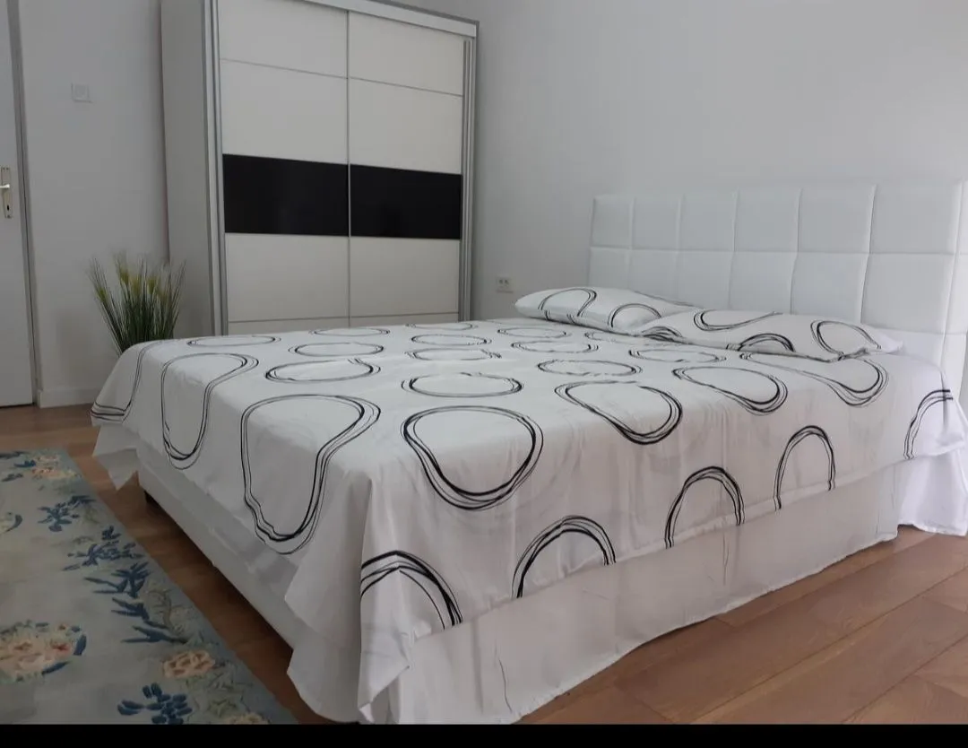 Svjetla spavaća soba sa velikim bračnim krevetom i ugradnim ormarom.