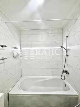 Smaller bathroom with a bathtub lined with marble tiles. - image 11