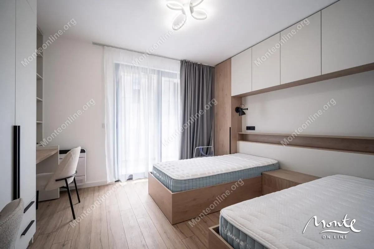 Moderna spavaća soba sa dva kreveta, radnim stolom i ugradnim ormarima.