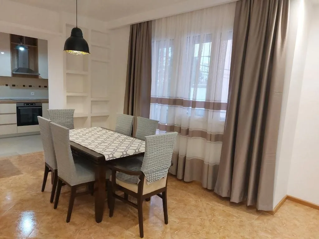 Dining area with a table, chairs, and a view of the curtained window.