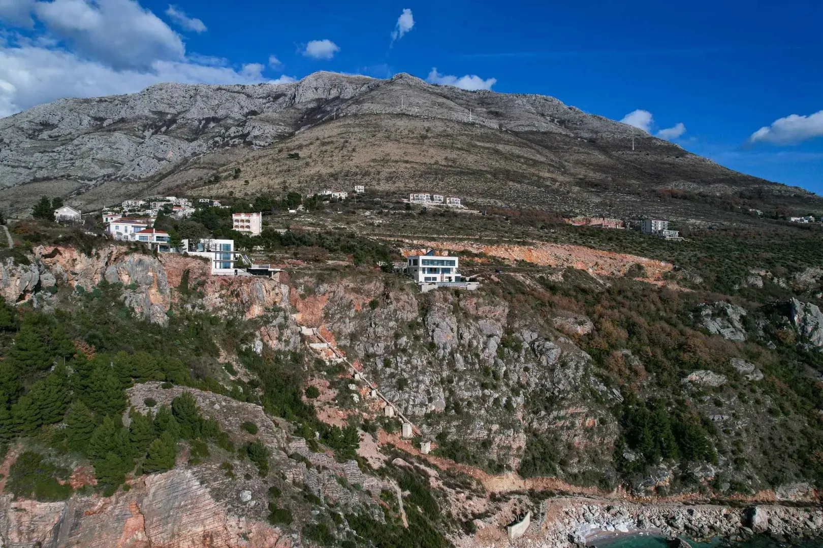 Pogled iz vazduha na kuće smještene na strmoj obali iznad mora.