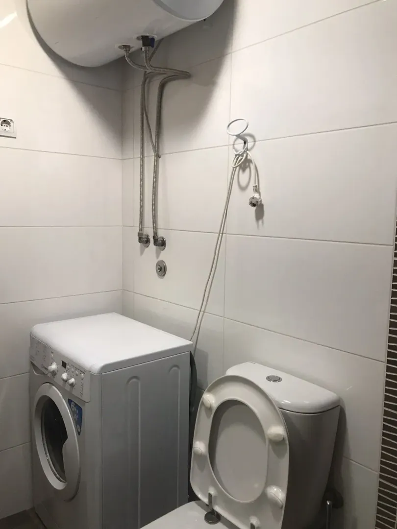 Part of the bathroom with a washing machine and a toilet.
