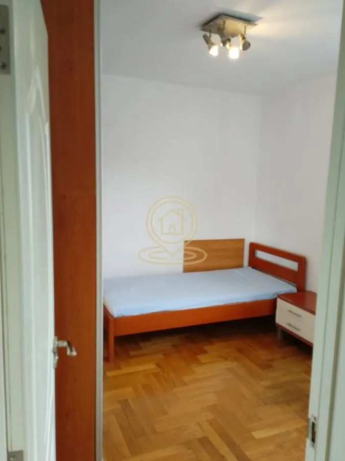 Pogled iz hodnika na manju spavaću sobu sa krevetom i parketom.