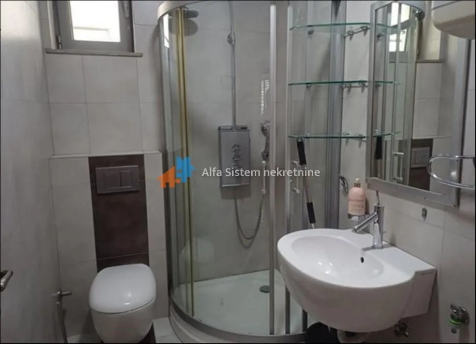 Bathroom equipped with a shower cabin, washbasin, toilet, and a mirror.