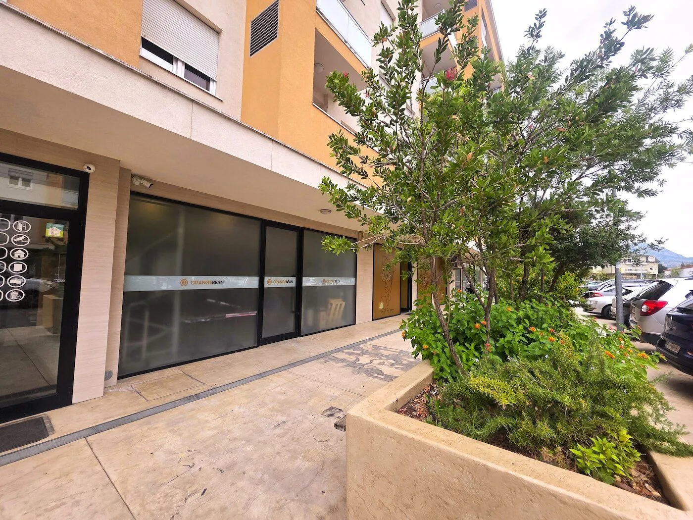 Exterior of a commercial space with a paved walkway and greenery in front of the entrance.