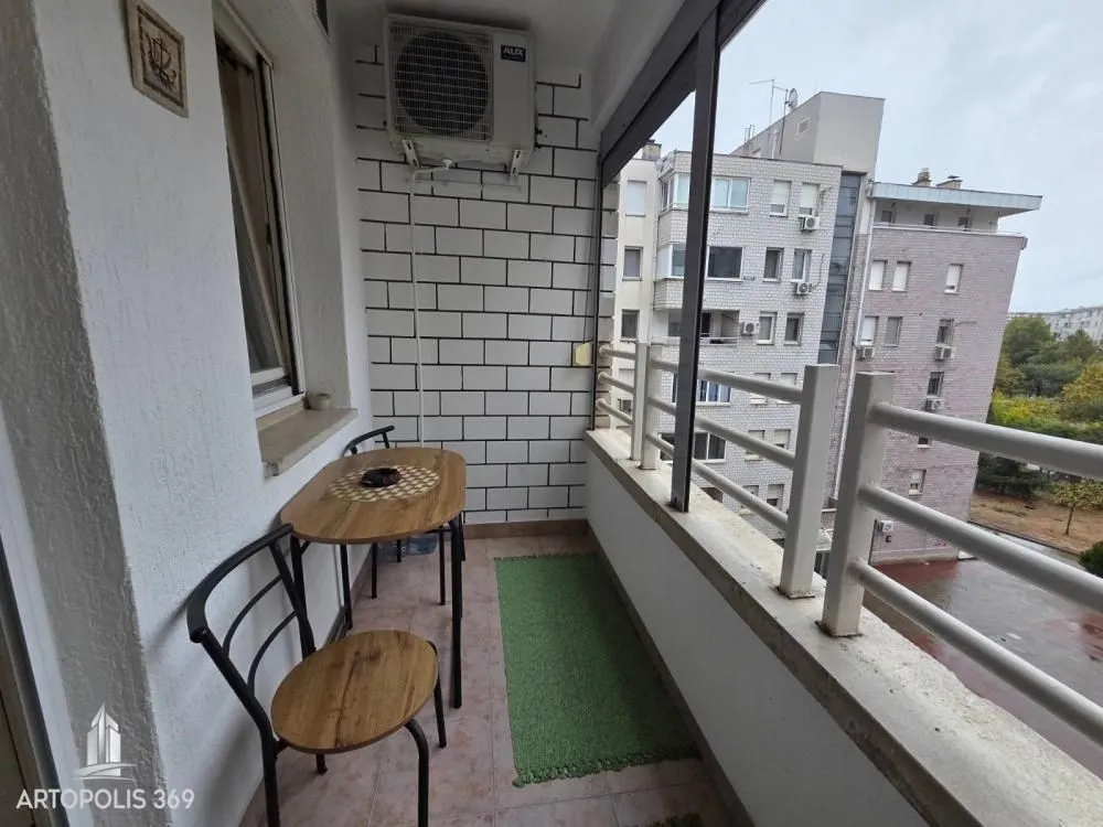 Manji zatvoreni balkon sa garniturom za sjedenje i pogledom na grad.