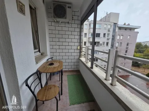 Manji zatvoreni balkon sa garniturom za sjedenje i pogledom na grad. - image 16