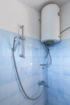 Dio kupatila sa tuš-baterijom i bojlerom na zidu obloženom pločicama. - image 20