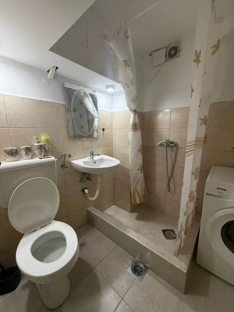 Small bathroom with a shower cabin, sink, toilet, and washing machine.