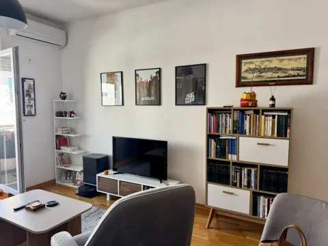 Dnevna soba sa policom za knjige, televizorom i garniturom za sedenje. - image 5