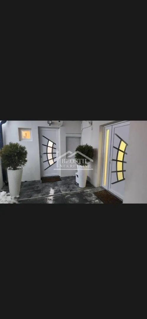 Entrance to the building with white doors and decorative planters.
