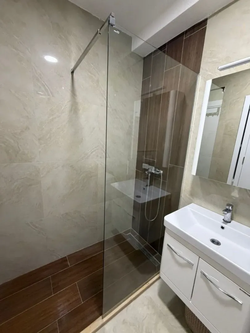 Modernly equipped bathroom with a walk-in shower and a sink cabinet.