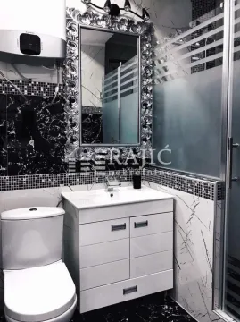 Modern bathroom with a vanity, toilet, and an ornate framed mirror. - image 8