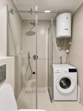 Bathroom with a shower cabin, washing machine, and water heater. - image 9