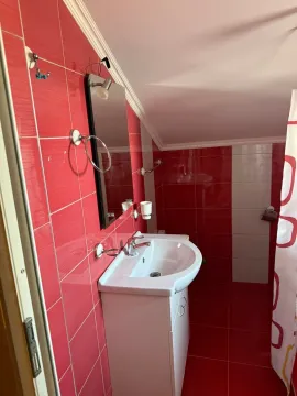 Small bathroom with a sink, mirror, and red tiles. - image 11