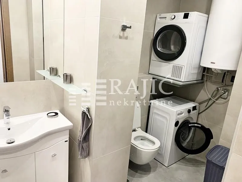 Modernly equipped bathroom with a washbasin, toilet, and washing machines.