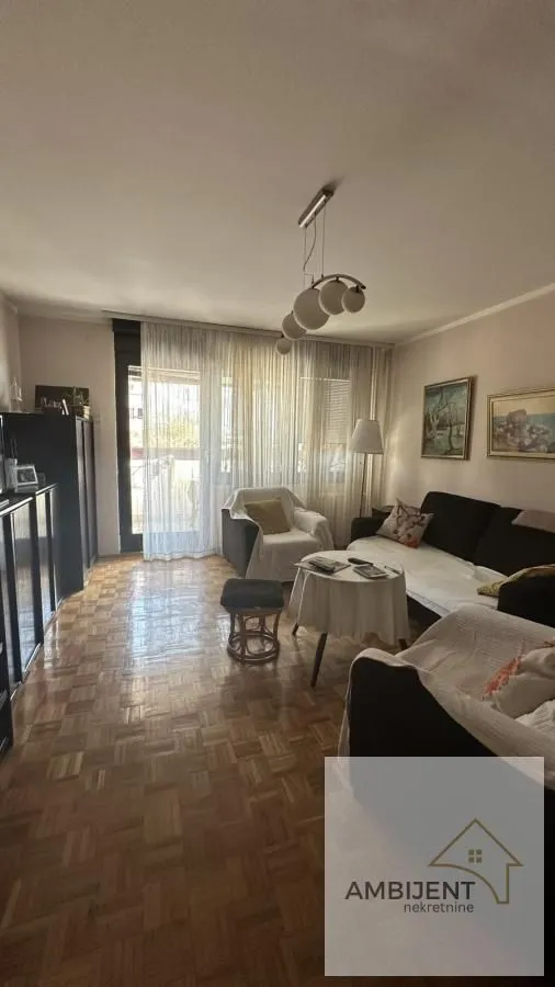 Living room with seating furniture and parquet flooring.