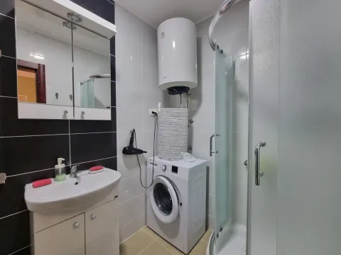 Bathroom with a sink, shower cabin, washing machine, and water heater. - image 5