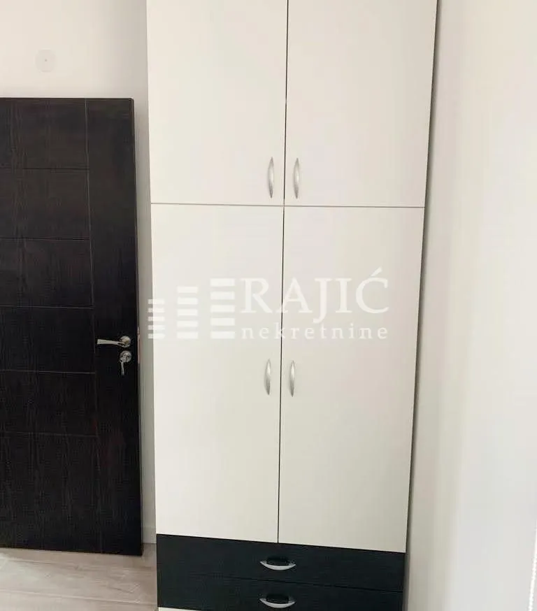 White wardrobe with black drawers and a dark door in a room.