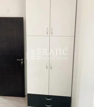 White wardrobe with black drawers and a dark door in a room. - image 9