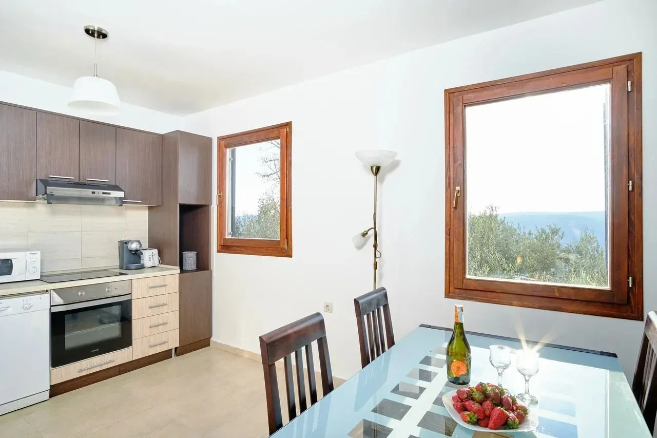 Bright kitchen with a dining table and windows overlooking nature.