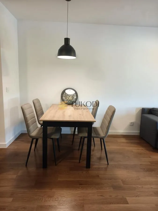 Dining area with a wooden table and upholstered chairs in a bright interior.