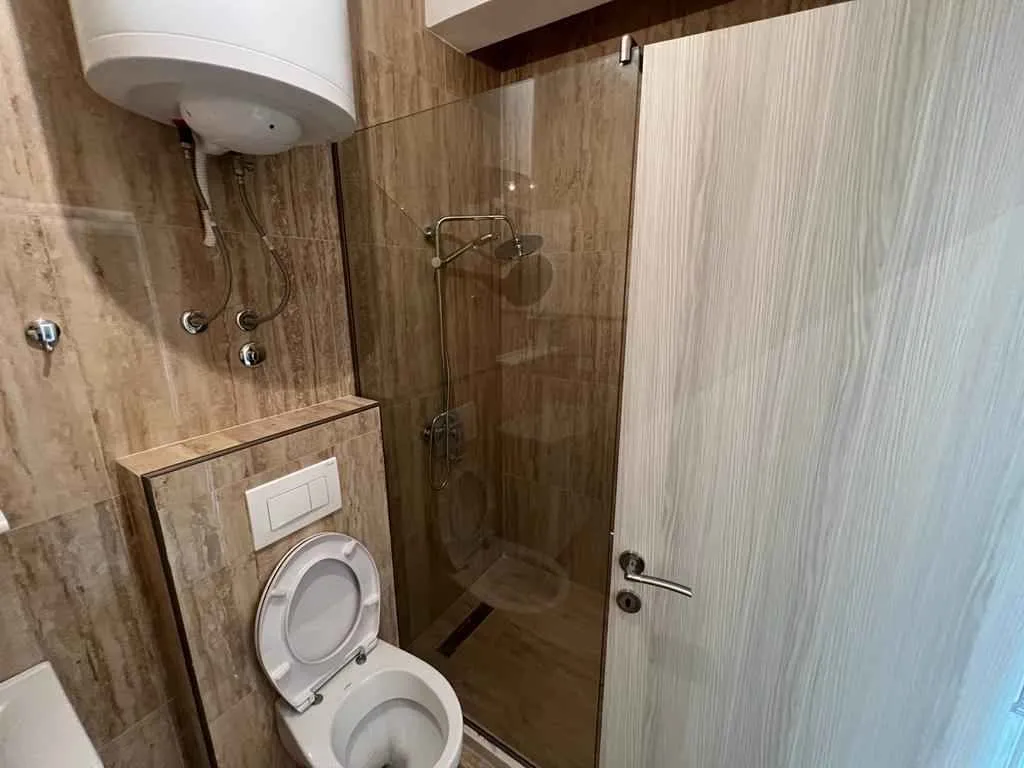 Moderno kupatilo sa tuš kabinom i toaletom.