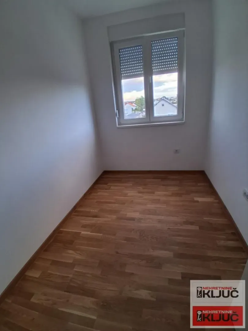 Prazna soba sa parketom i prozorom.
