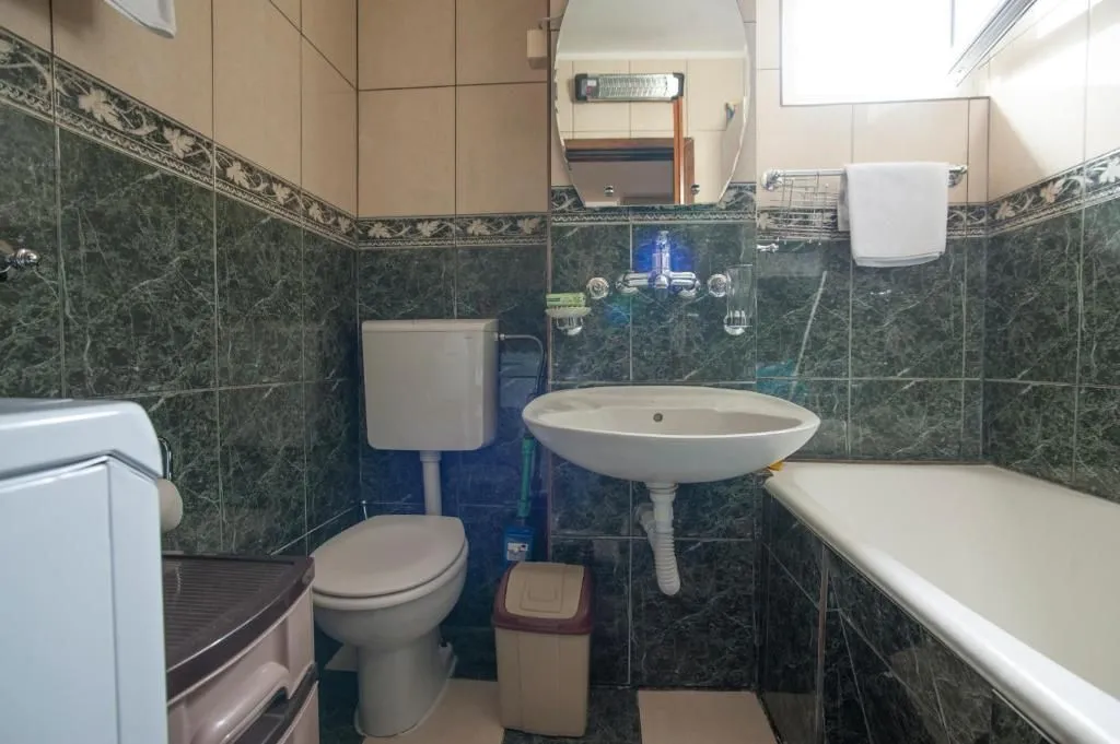 Small tiled bathroom with a bathtub, sink, and toilet.
