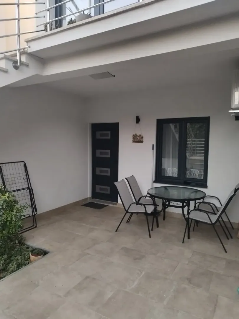 Natkriveni dio dvorišta sa garniturom za sjedenje ispred ulaznih vrata.