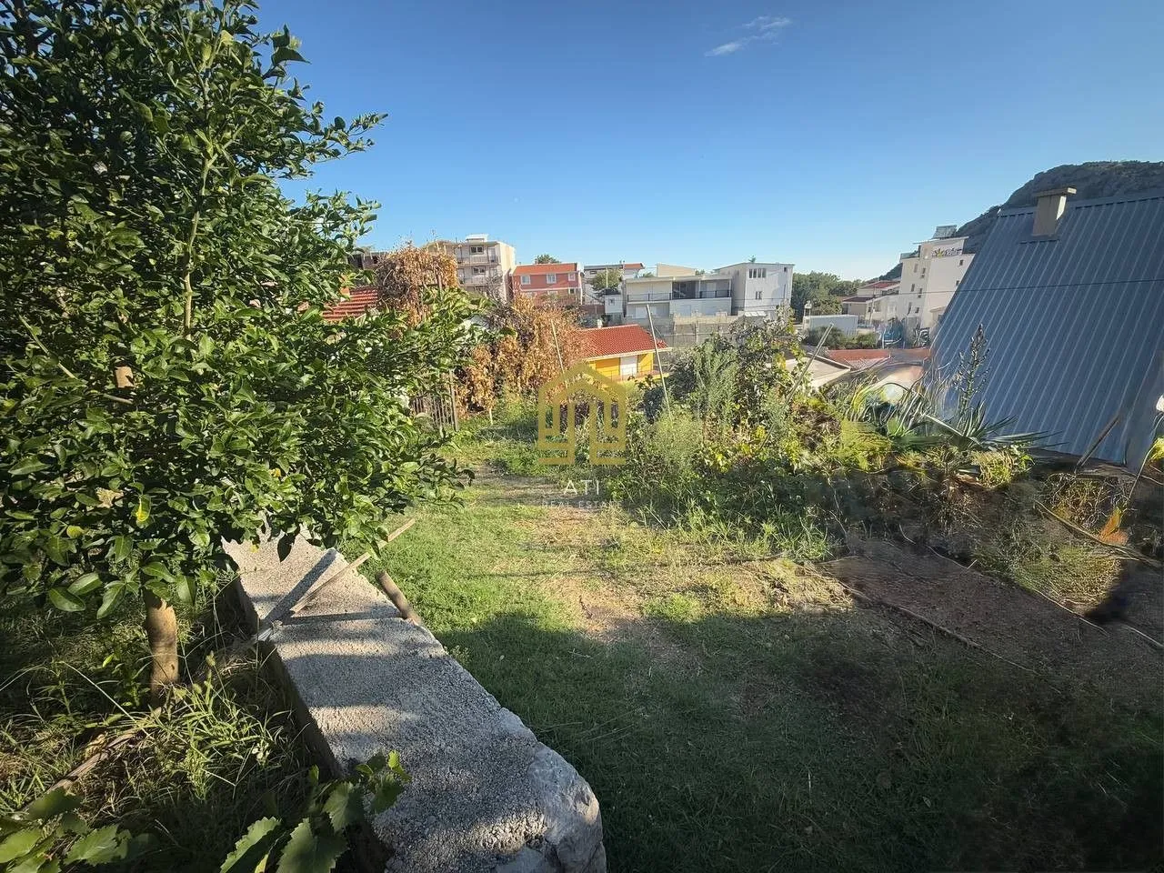 Dvorište sa zelenilom i pogledom na naselje i brda.