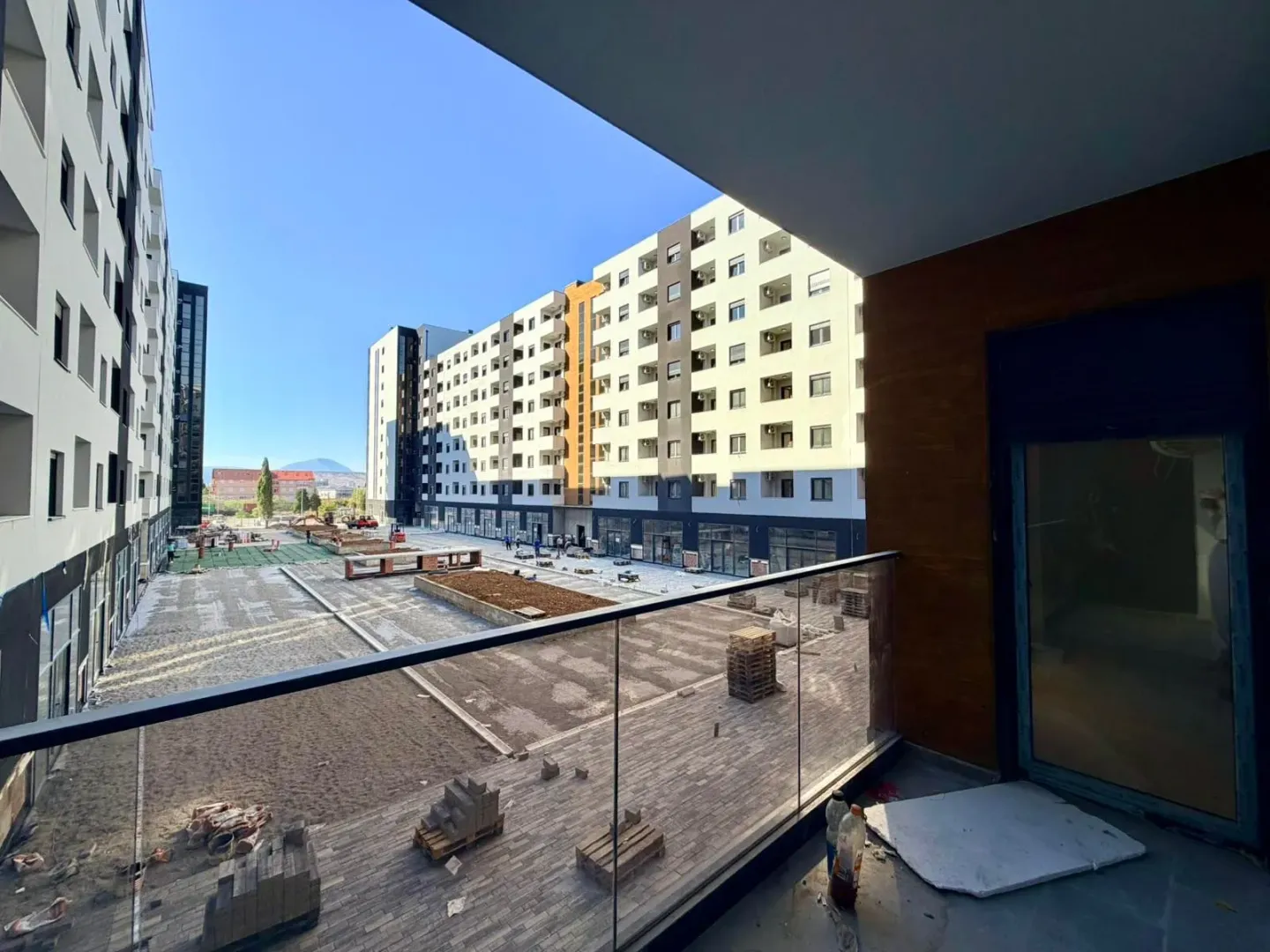 Pogled sa balkona na dvorište i okolne zgrade u izgradnji.