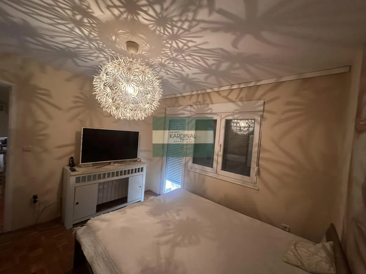 Spavaća soba sa bračnim krevetom, televizorom i lusterom sa posebnim efektom svetlosti na plafonu.