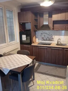 Kitchen with dark wooden units and a dining table. - image 3