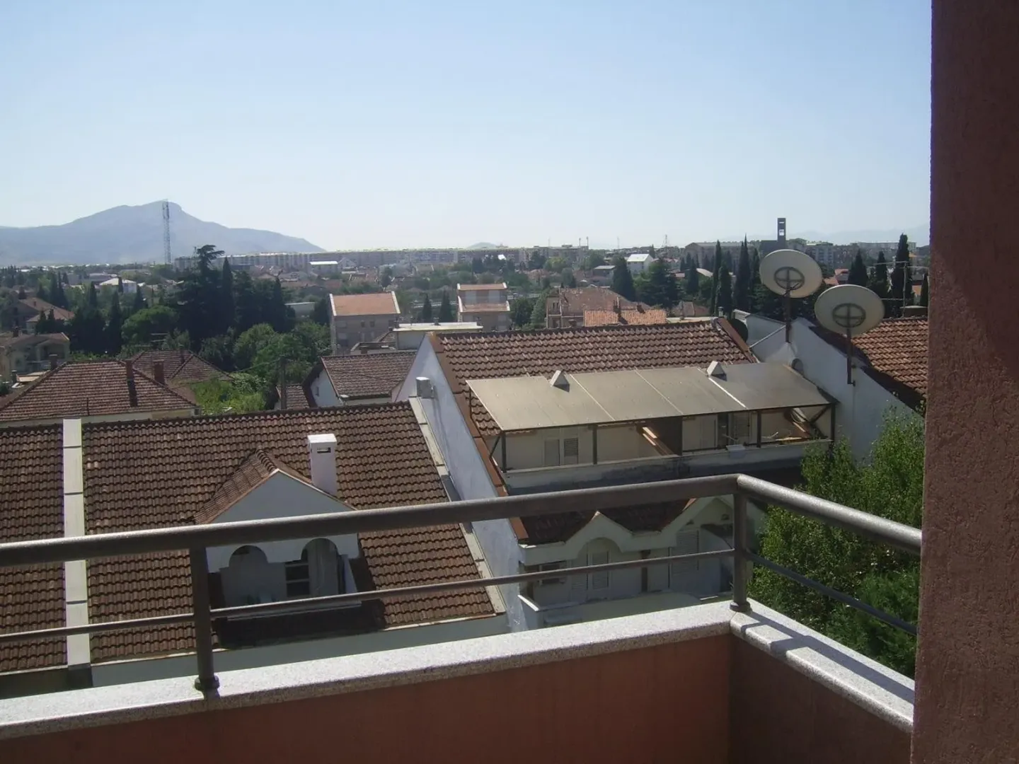 Pogled sa balkona na okolna naselja i planine u daljini.