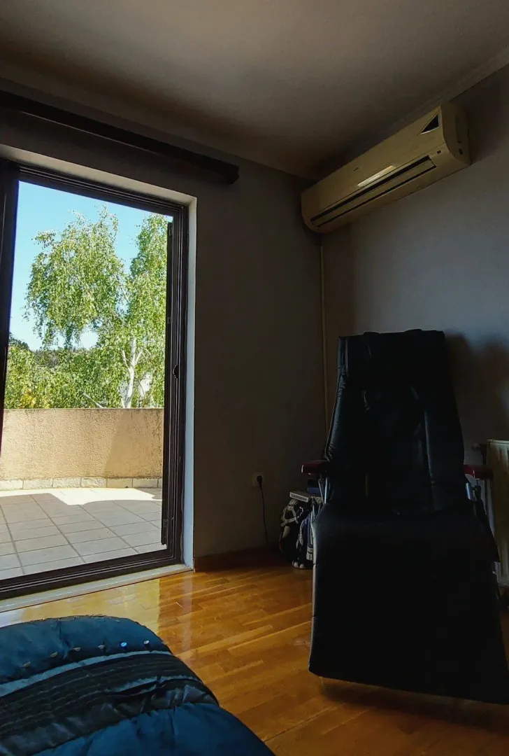 A room with wooden flooring, a leather armchair, and terrace access.