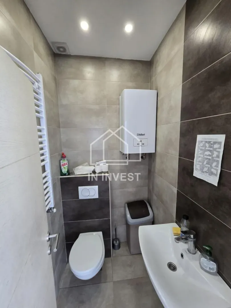 Smaller tiled bathroom with a toilet, washbasin, and water heater.
