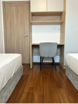 Modern bedroom with beds, a desk, and a wooden door. - image 12
