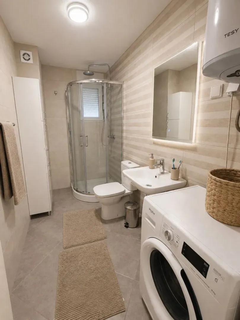 Modern bathroom with a shower cabin and a washing machine.