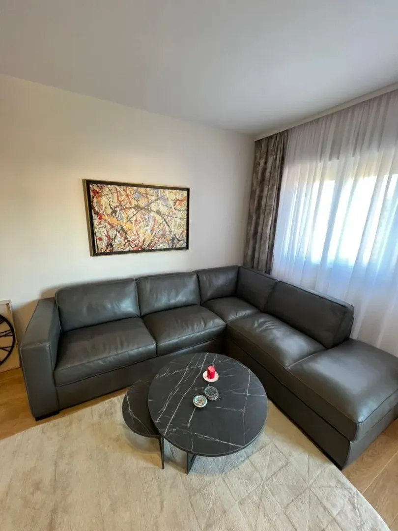 Living room with a sectional sofa, a round coffee table, and an artwork on the wall.