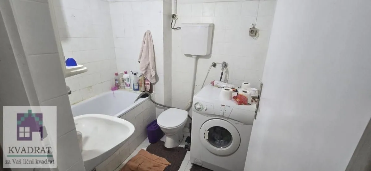 Manje kupatilo sa kadom, wc šoljom, umivaonikom i veš mašinom.