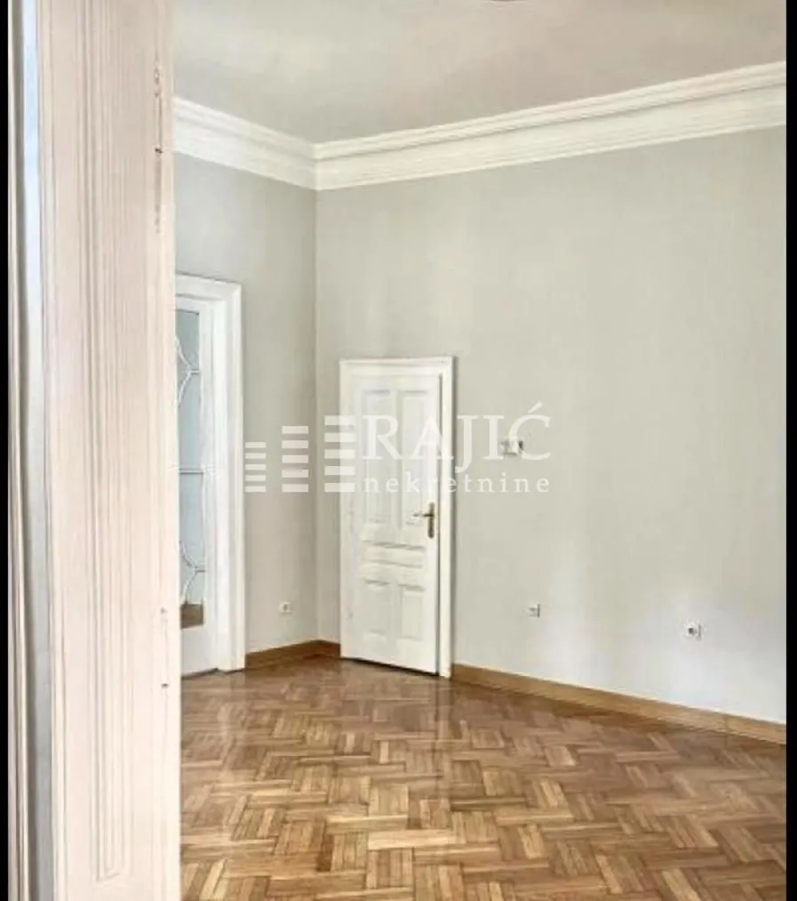 Empty room with parquet flooring and a white door.