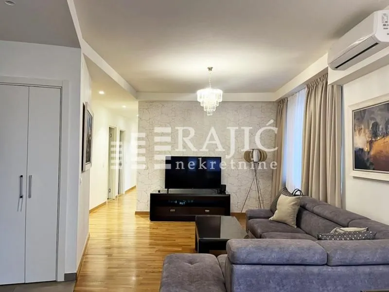 Spacious and bright living room with seating furniture and a TV.
