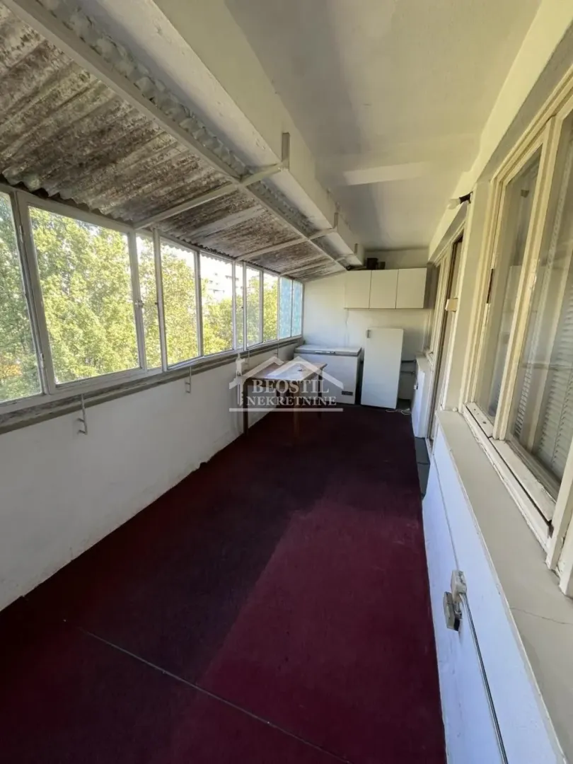 Enclosed balcony with large windows and a view of greenery.