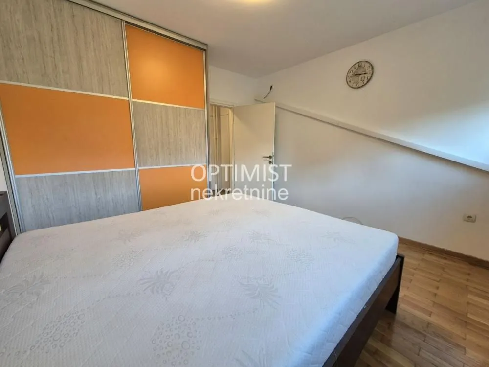 Furnished bedroom with a double bed and a large fitted wardrobe.