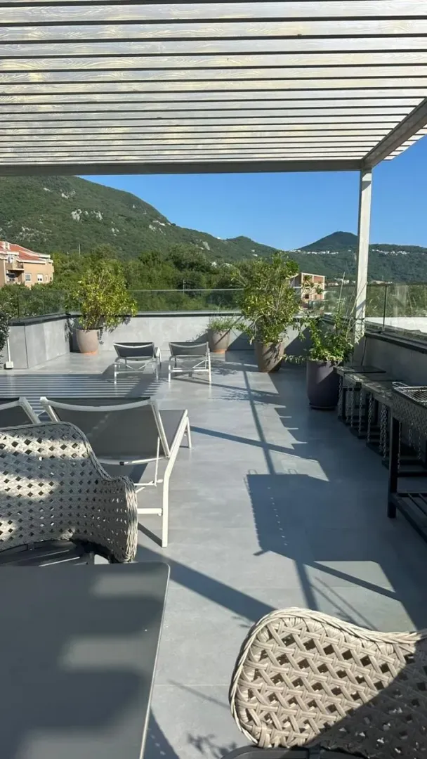 Prostrana krovna terasa sa garniturom za sjedenje i pogledom na planine.