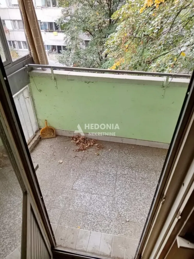 Manji balkon sa pogledom na drveće.
